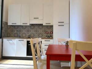 a kitchen with white cabinets and a red table and chairs at Guest House SanSiro Fiera in Milan