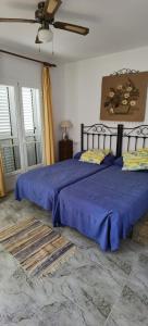 a bedroom with two beds with blue sheets and a fan at Duplex en urbanización con piscina comunitaria y wifi in Mojácar