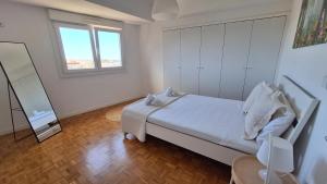 a white bedroom with a bed and a mirror at Apartamentos Jardim do Morro in Vila Nova de Gaia