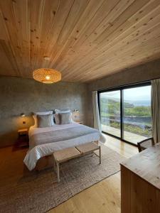 um quarto com uma cama grande e uma janela grande em Casa do Alecrim em São Roque do Pico