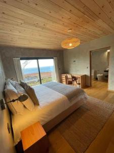 a bedroom with a large bed with a large window at Casa do Alecrim in São Roque do Pico