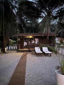 a resort with two benches and a building with palm trees at Mamagoa Beach Resort in Mandrem