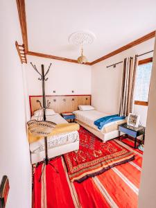two beds in a room with a red carpet at Gite Panorama in Imlil