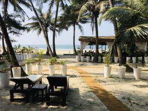a table and chairs on a beach with palm trees at Mamagoa Beach Resort in Mandrem