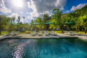a swimming pool with chairs and umbrellas at Puri Garden Penida in Nusa Penida +31 photos