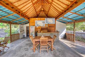 an outdoor dining room with a wooden table and chairs at Puri Garden Penida in Nusa Penida