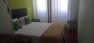 um pequeno quarto com uma cama com almofadas verdes em Hotel Paulista em Porto