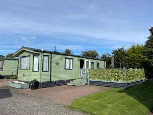 a green tiny house sitting on a driveway at 6 Rannoch, lovely holiday static caravan for dogs & their owners. in Forfar