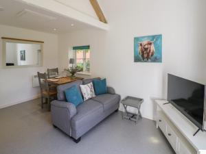 uma sala de estar com um sofá, uma mesa e uma televisão em Chapel Cottage em Pershore