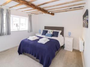 a white bedroom with a large bed with blue sheets at Chapel Cottage in Pershore