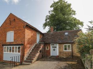 uma antiga casa de tijolos com uma porta branca e escadas em Chapel Cottage em Pershore