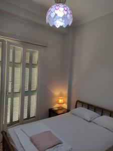 a bedroom with a bed and a chandelier at Lemon Apartment near to Pireaus Port in Piraeus