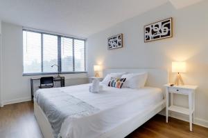 a white bedroom with a large white bed and a desk at Modern & Charming Apt With Rooftop @pentagon City in Arlington