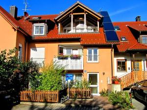 ein Haus mit einem orangenen Dach und einem weißen Zaun in der Unterkunft Ferienwohnungen Shamal in Reutin