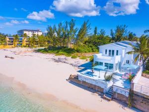 a white house on a beach with the ocean at Modern, Stunning Bright Central Beach Villa in Nassau