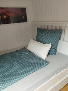 a bed in a small room with blue and white pillows at Apartment Wittorf in Neumünster