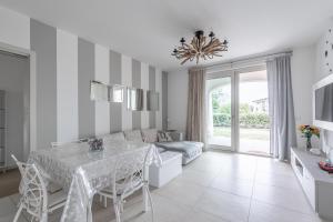 sala de estar blanca con mesa y sofá en Lakefront Nuova Riva - by Host4U, en Padenghe sul Garda