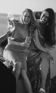 dos mujeres sentadas en un sofá sosteniendo copas de vino en 7Pines Resort Ibiza, part of Destination by Hyatt, en San José