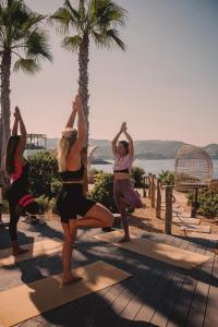 a group of women doing yoga on a deck at 7Pines Resort Ibiza, part of Destination by Hyatt in San Jose