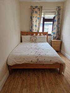 1 dormitorio con 1 cama con cabecero de madera y ventana en 5,Bulfin Road, en Nenagh