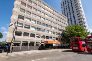 dois autocarros de dois andares estacionados em frente a um edifício em easyHotel Croydon em Croydon