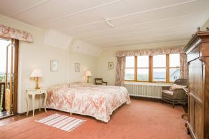 a bedroom with a bed and a chair and windows at Villa de Duintop in Bergen aan Zee