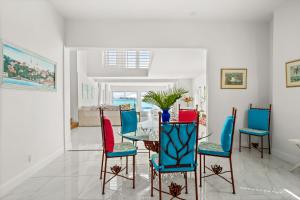 ナッソーにあるModern, Stunning Bright Central Beach Villaのダイニングルーム(ガラスのテーブル、カラフルな椅子付)
