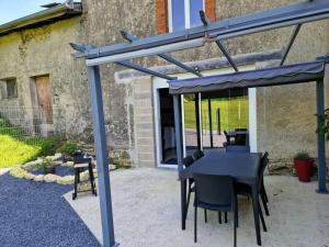 un patio con una mesa negra y sillas bajo una pérgola en Gîte de l'étoile, 6 pers. spacieux avec extérieur, 