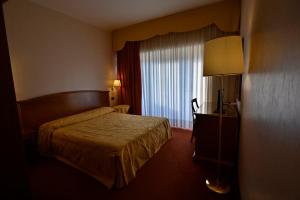 Villa Sirena Hotel e Ricevimenti في Durazzano: غرفه فندقيه بسرير ونافذه