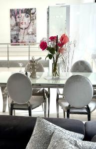 uma sala de jantar com uma mesa de vidro com cadeiras e flores em JB City Loft em Hamburgo