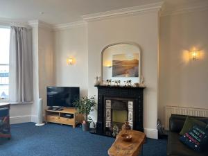 a living room with a fireplace and a mirror at One Queens Gardens, Sea View Apartment, Eastbourne. in Eastbourne