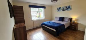 a bedroom with a bed with a blue blanket and a window at 6 Bedroom Spacious villa, Free Parking in Byfleet