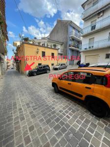 um camião laranja estacionado numa rua com edifícios em Raffinato Open Space em Orsogna