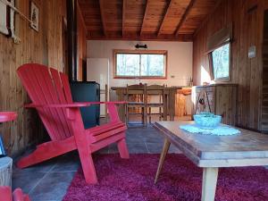 una sala de estar con 2 sillas rojas y una mesa. en Cabaña Orilla de Río, en Coñaripe