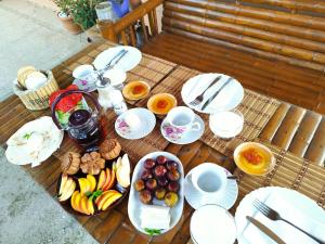 einen Tisch mit Teller mit Lebensmitteln und Obst darauf in der Unterkunft Country House Uliana in Zqaltubo