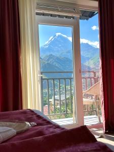 a bedroom with a view of a mountain through a window at Planet kazbegi in Stepantsminda