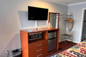 a room with a television on a dresser with a bed at The Islander Motel Santa Cruz in Santa Cruz