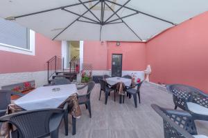 un patio con tavoli, sedie e parete rosa di Affittacamere SS. Smile a Loreto