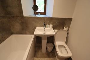 a bathroom with a sink and a toilet and a tub at Barlow Country Club - Mill Farm Cottages in Dronfield +71 photos