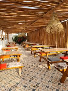 a row of wooden tables and benches in a restaurant at La Maison des Vagues in Sidi Kaouki