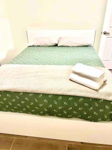 Una cama con un edredón verde con toallas. en Pristine 2/1 Duplex, Private Home Sanctuary; Patio, en Fort Myers