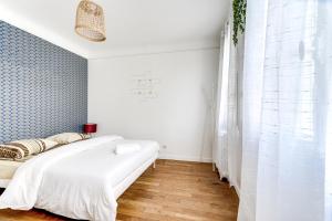 een slaapkamer met een wit bed en een blauwe muur bij Chic apart Paris - La defense in Courbevoie