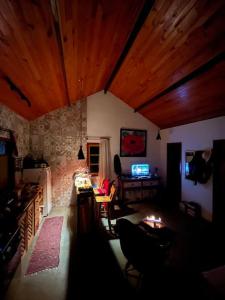 uma sala de estar com tectos em madeira e um quarto com uma mesa em chalé completo na fazenda em Bocaina de Minas