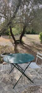 una mesa y una silla junto a un árbol en Sous les oliviers, en Tourrettes