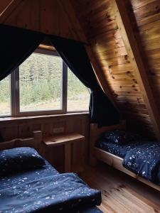 two beds in a cabin with a window at Nomad Lodge Zminica in Žabljak