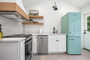 a kitchen with white cabinets and a blue refrigerator at Charming Saints Street Cottage in Lafayette