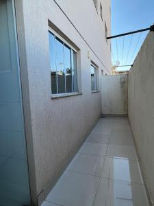 einen leeren Flur eines Gebäudes mit Fenster in der Unterkunft Apartamento Completo - Algarve 203 e 204 in Patos de Minas