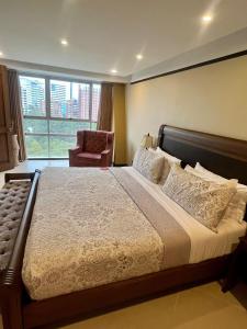 a bedroom with a bed with a chair and a window at Hotel Du Parc in Medellín