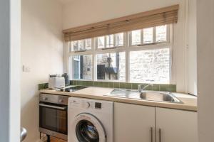 cocina con fregadero y lavadora en Look No Further The Stable Block in Beautiful Beaufort House 2 Bedrooms en Bath
