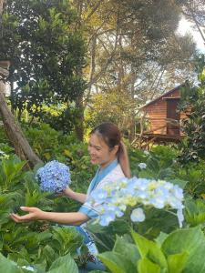uma jovem com um ramo de flores azuis em Mộc Hương farmstay 